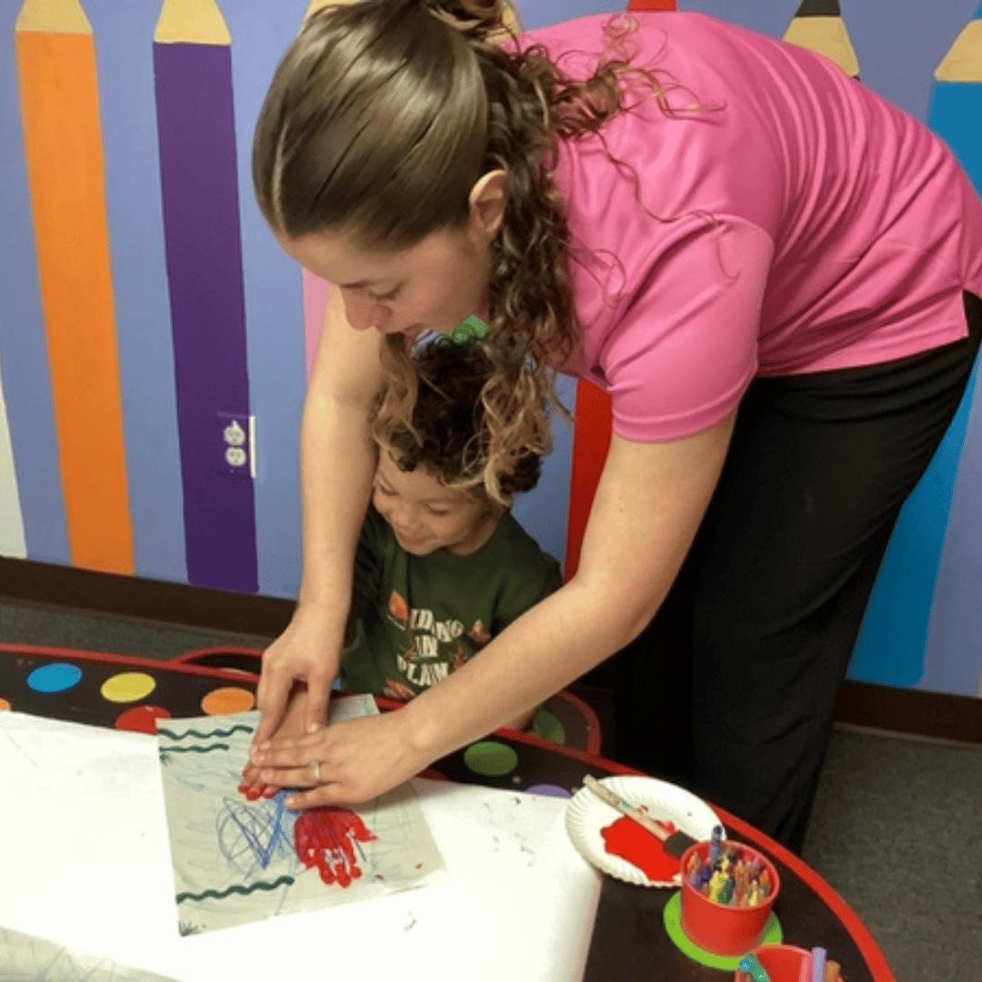 Person helping a child with a handprint craft
