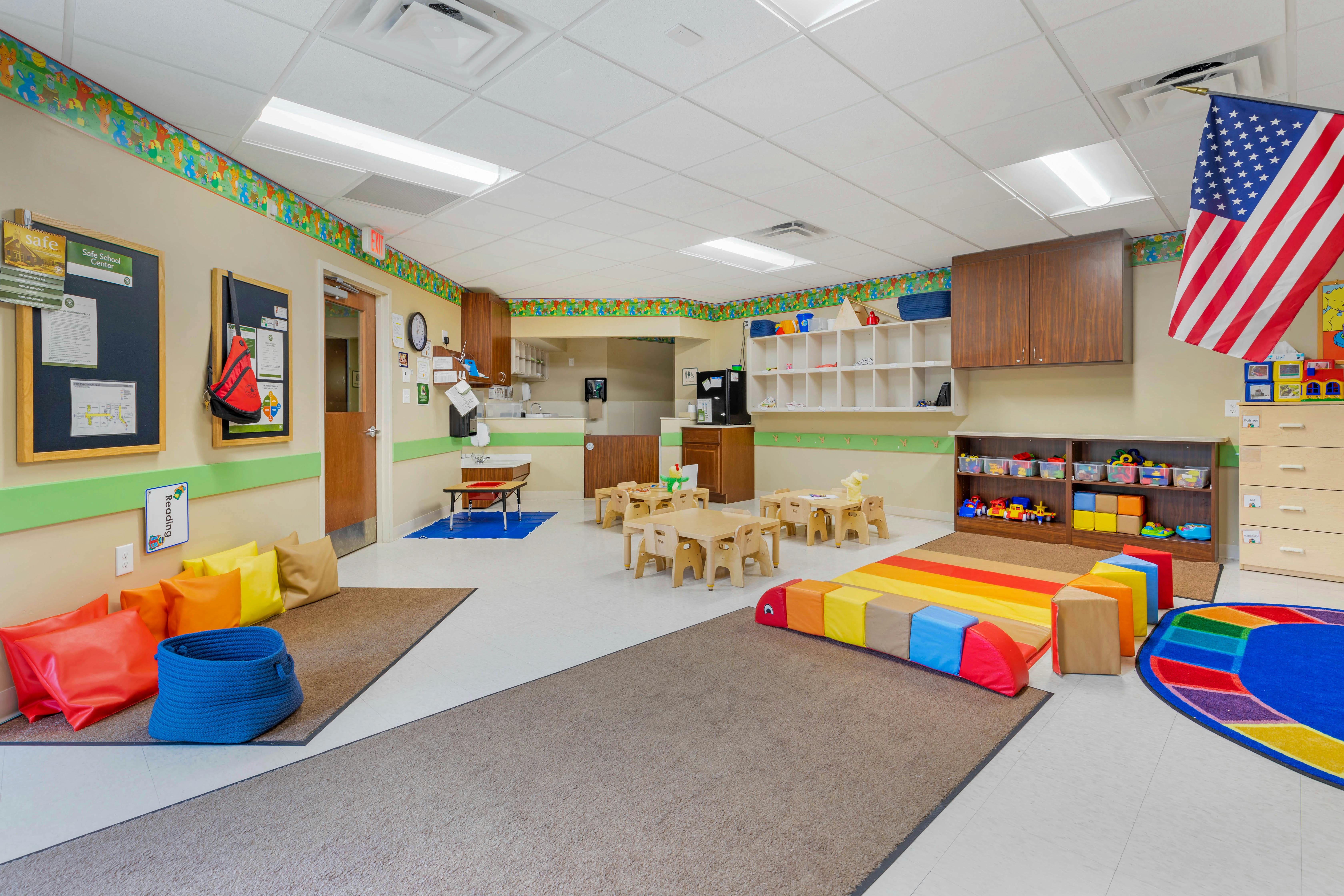 Classroom with small tables and chairs, bulletin boards, and an American flag