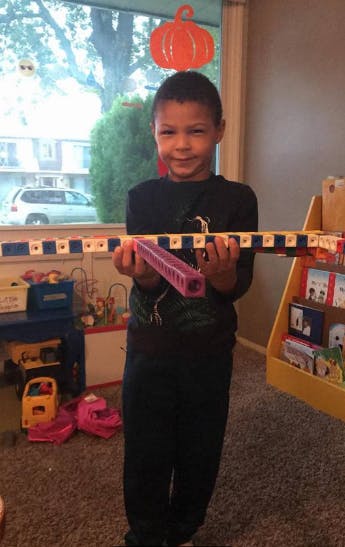 Child holding a long toy with a purple piece in the middle