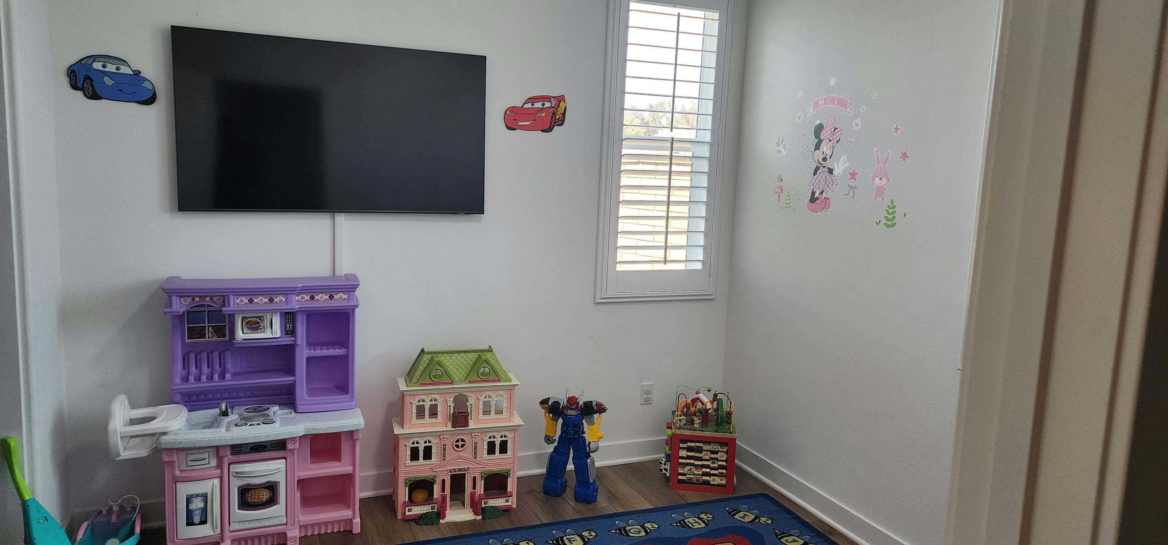 Playroom with a television, toy kitchen, dollhouse, and other toys