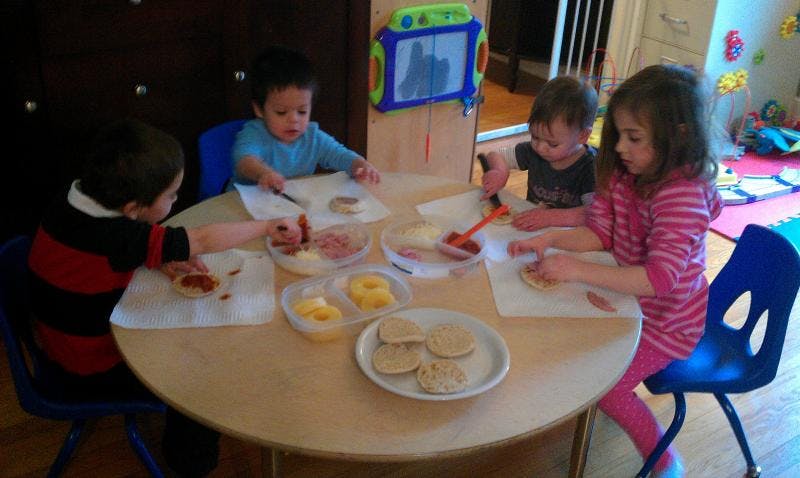 Four children sitting around a table making food