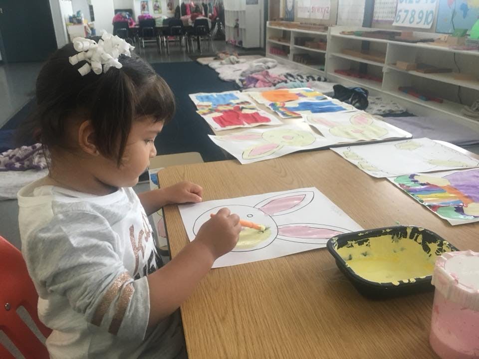 Child coloring a bunny drawing at a table