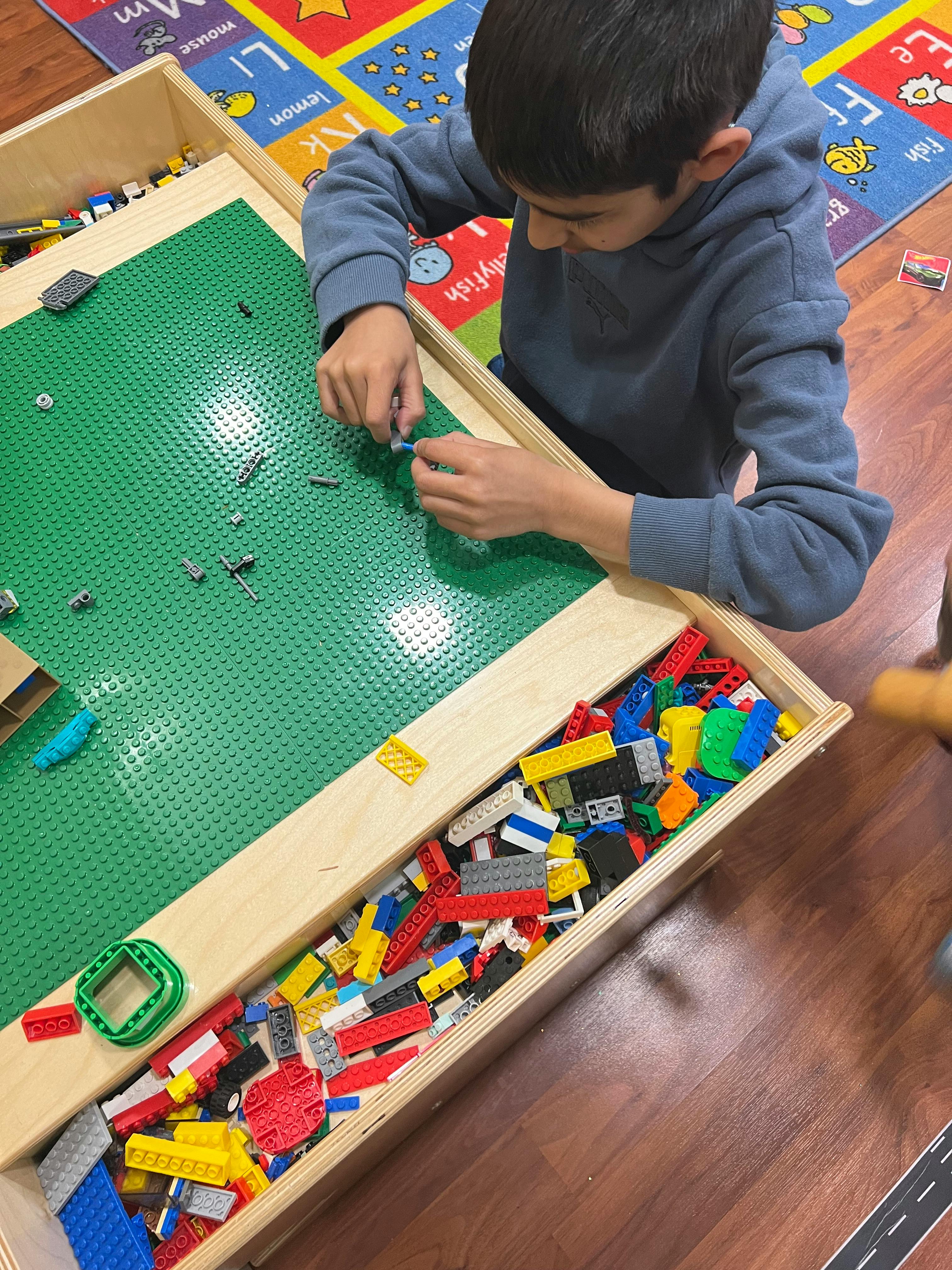 Child playing with building blocks on a green baseplate