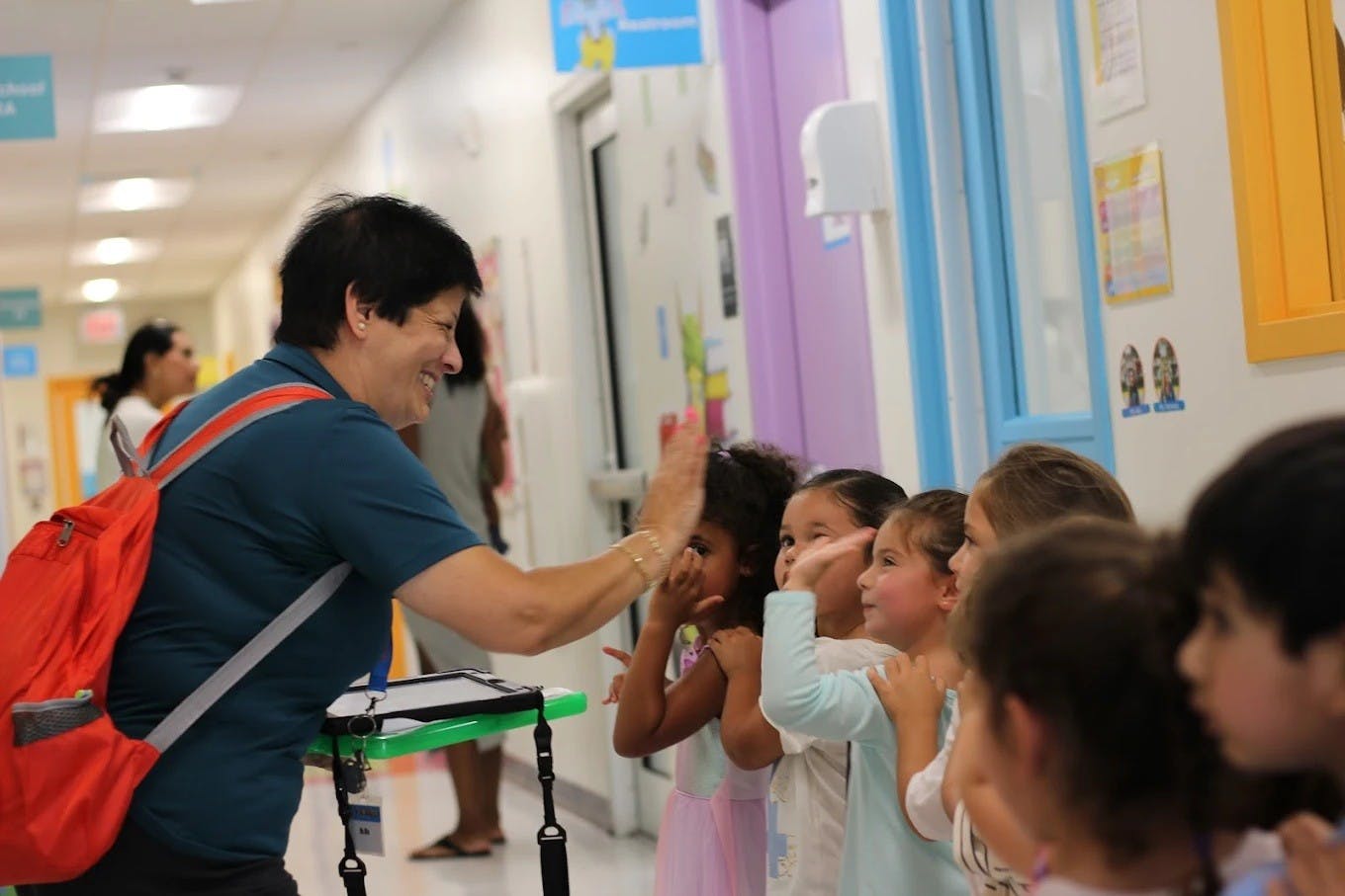 Adult giving high-fives to children in a hallway
