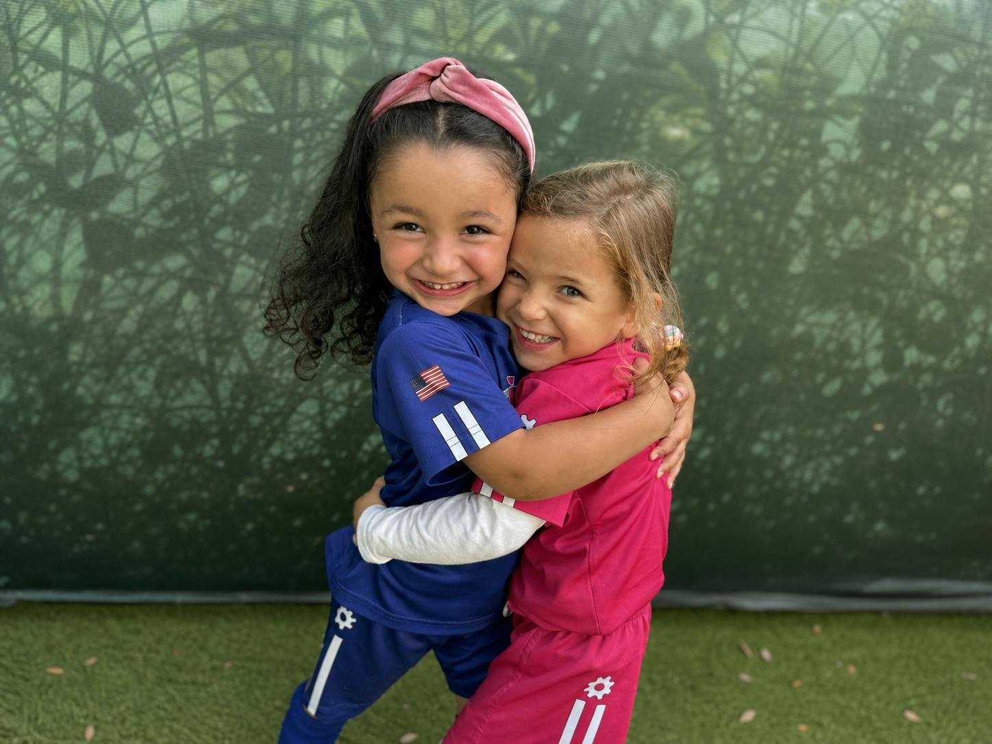 Two children wearing sports uniforms hugging