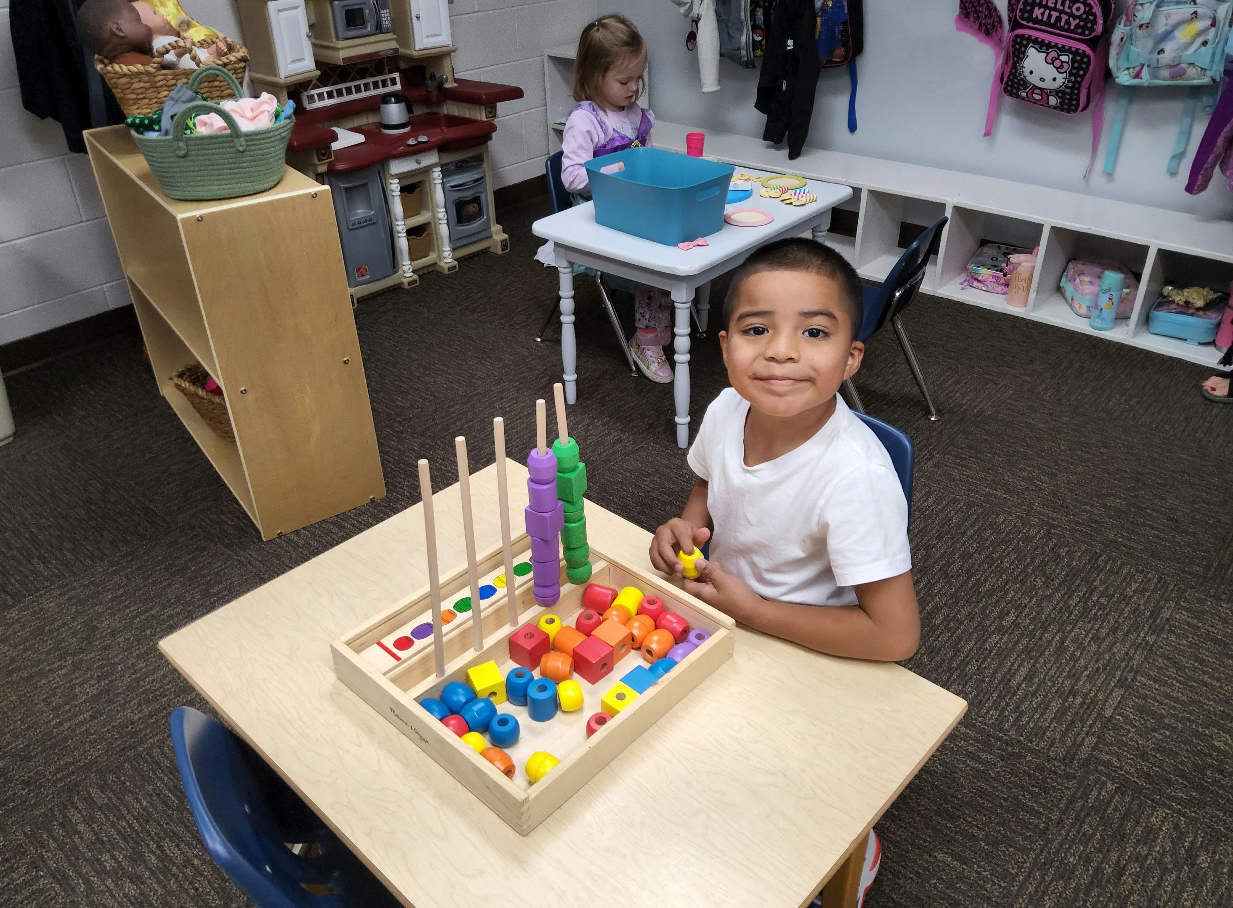 Child playing with colorful blocks and pegs at a table
