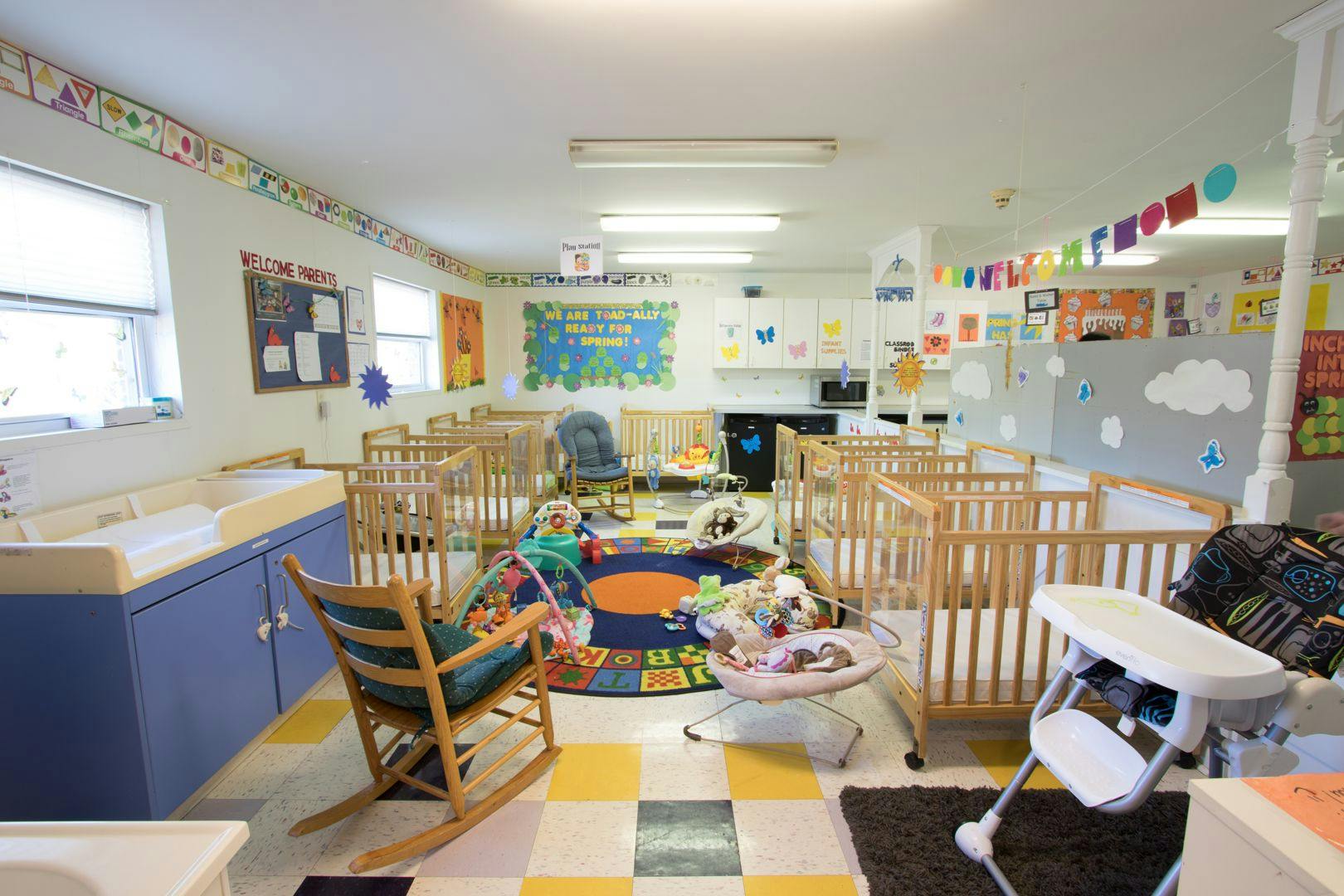 Nursery room with multiple cribs, changing station, and play area