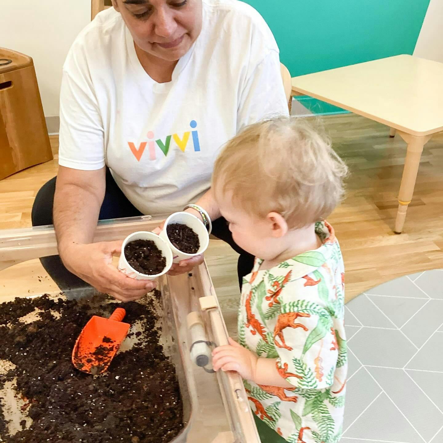 Person and child holding small cups of soil