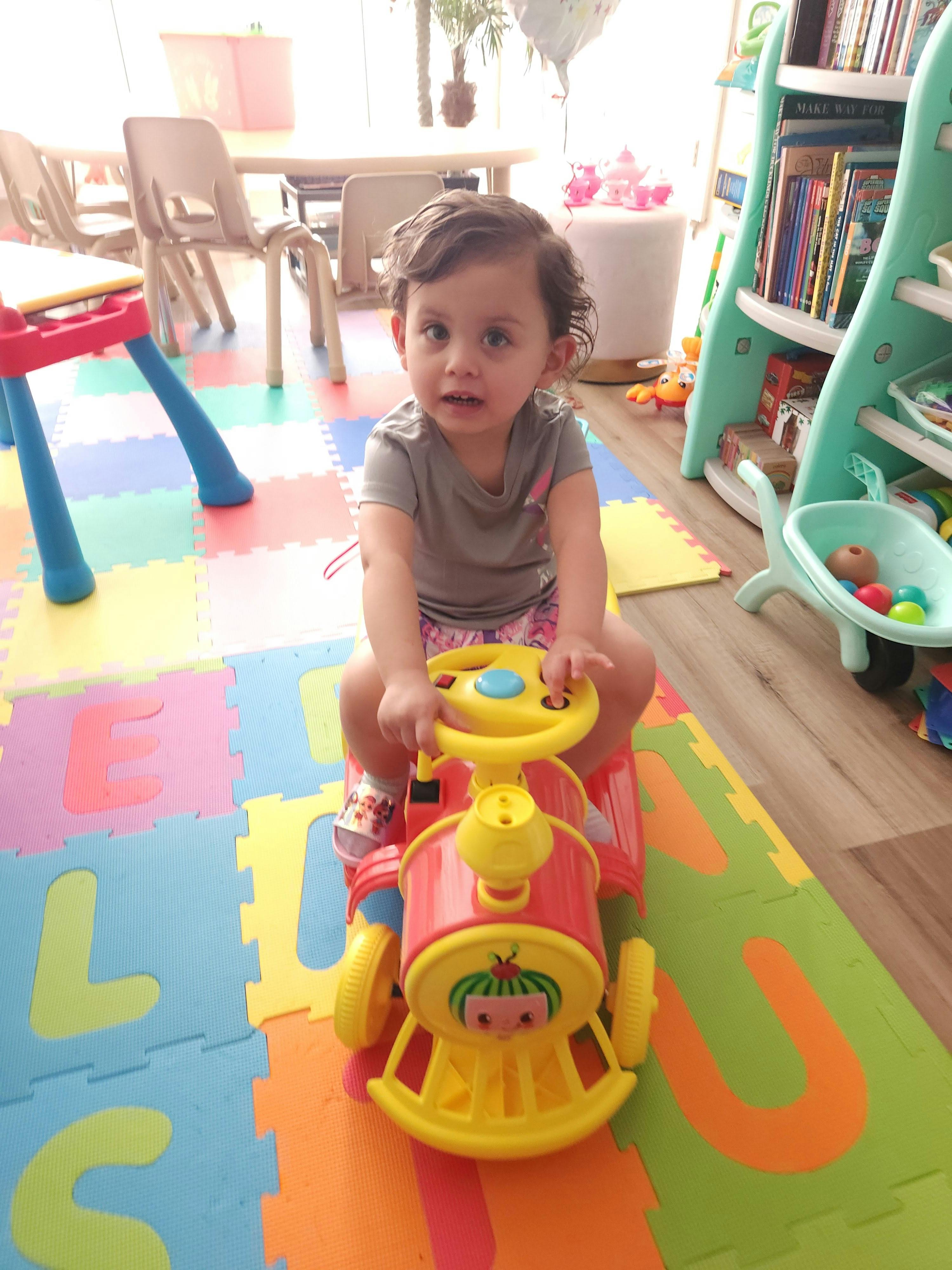 Child on a toy ride-on train in a playroom