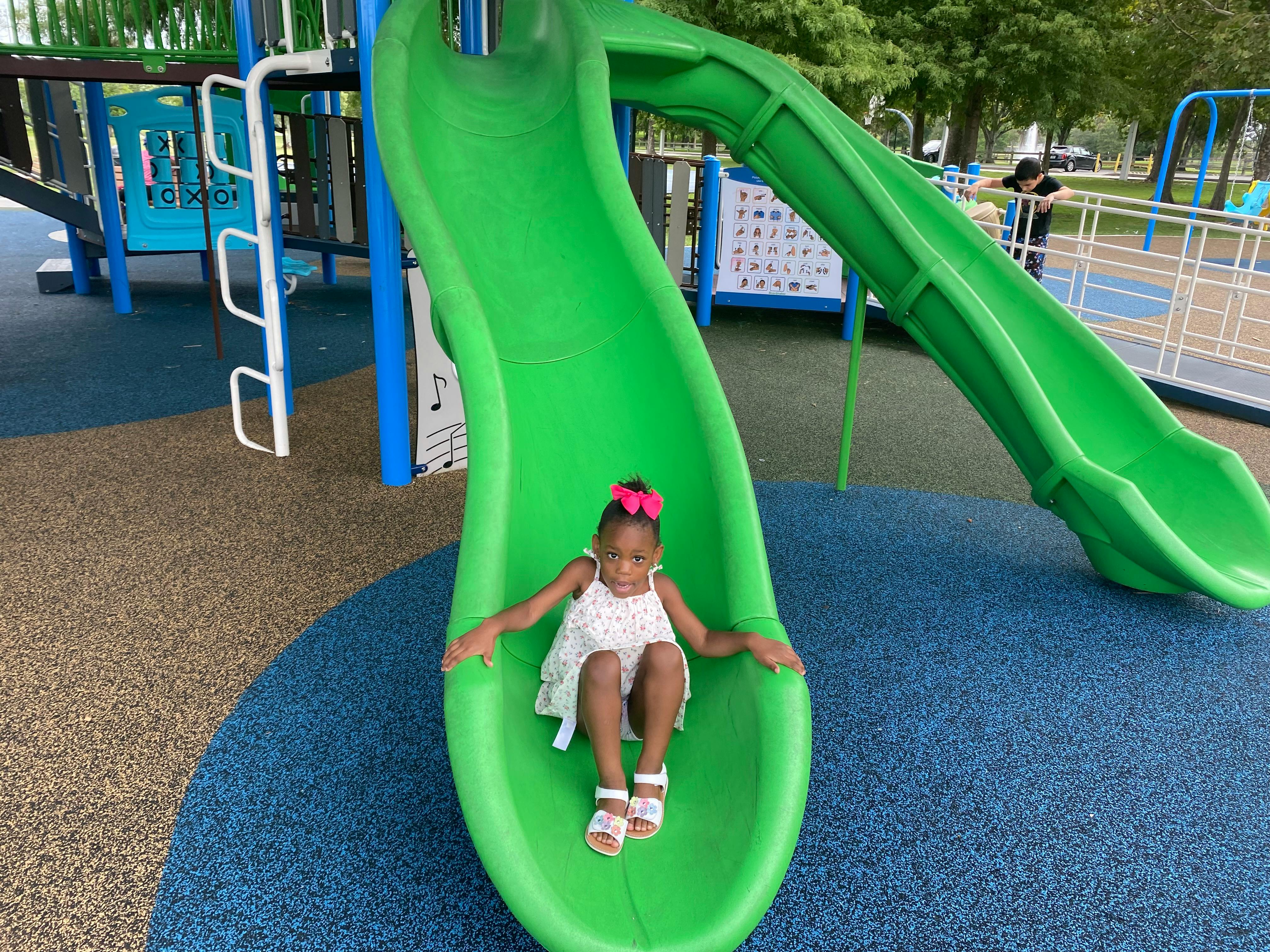 Child sitting on a green playground slide