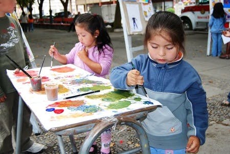 Two children painting on a large sheet of paper