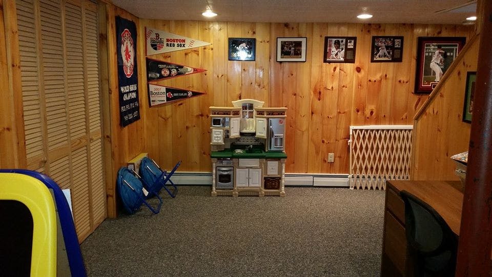 Basement room with wood paneling, carpet, and a play kitchen
