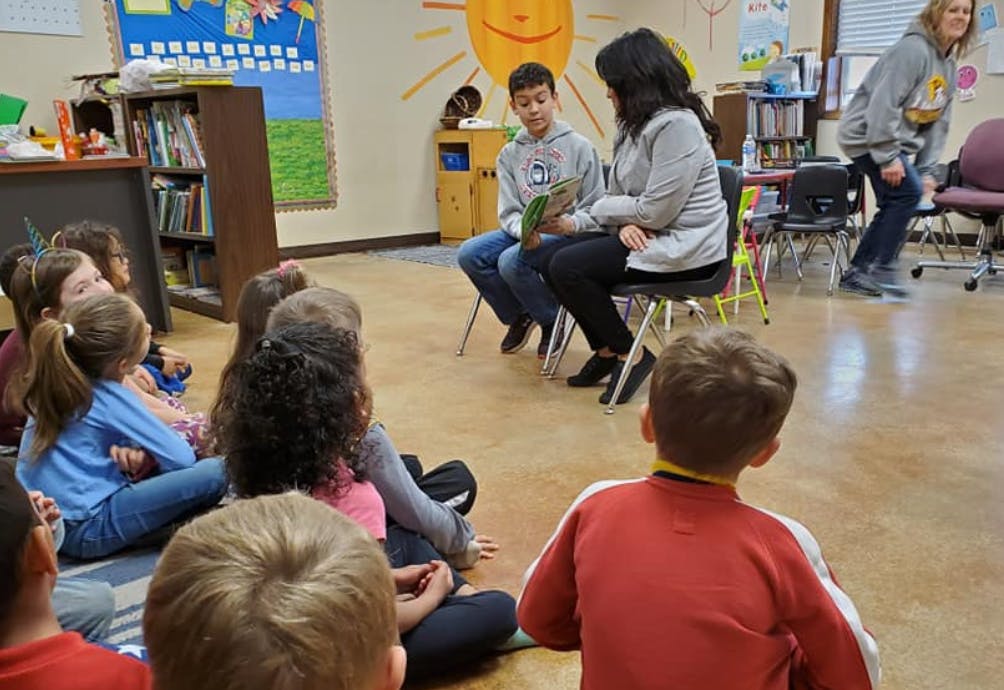 Children sitting on the floor listening to a person reading a book