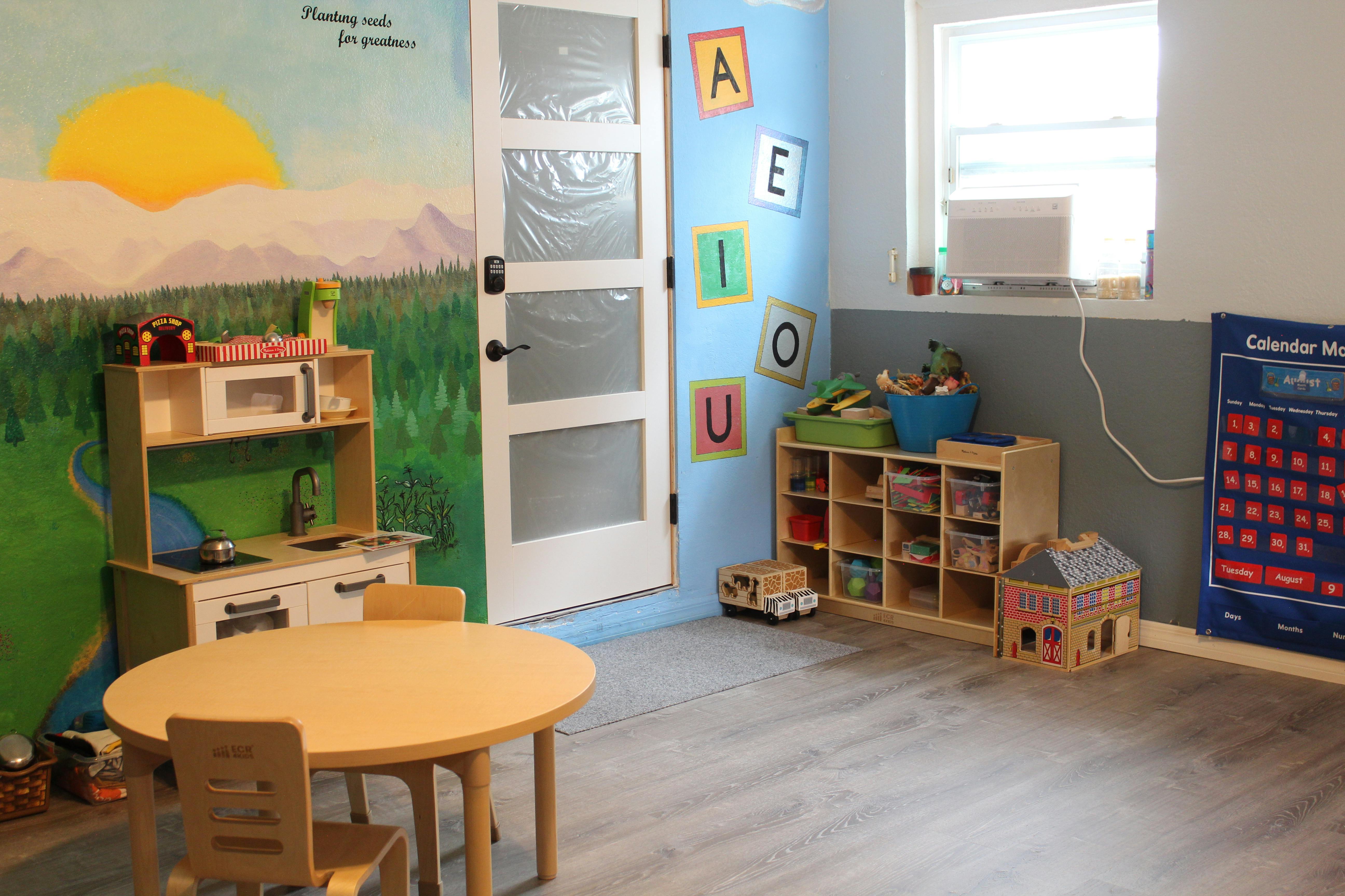 Playroom with small table and chairs, toy kitchen, and storage shelves