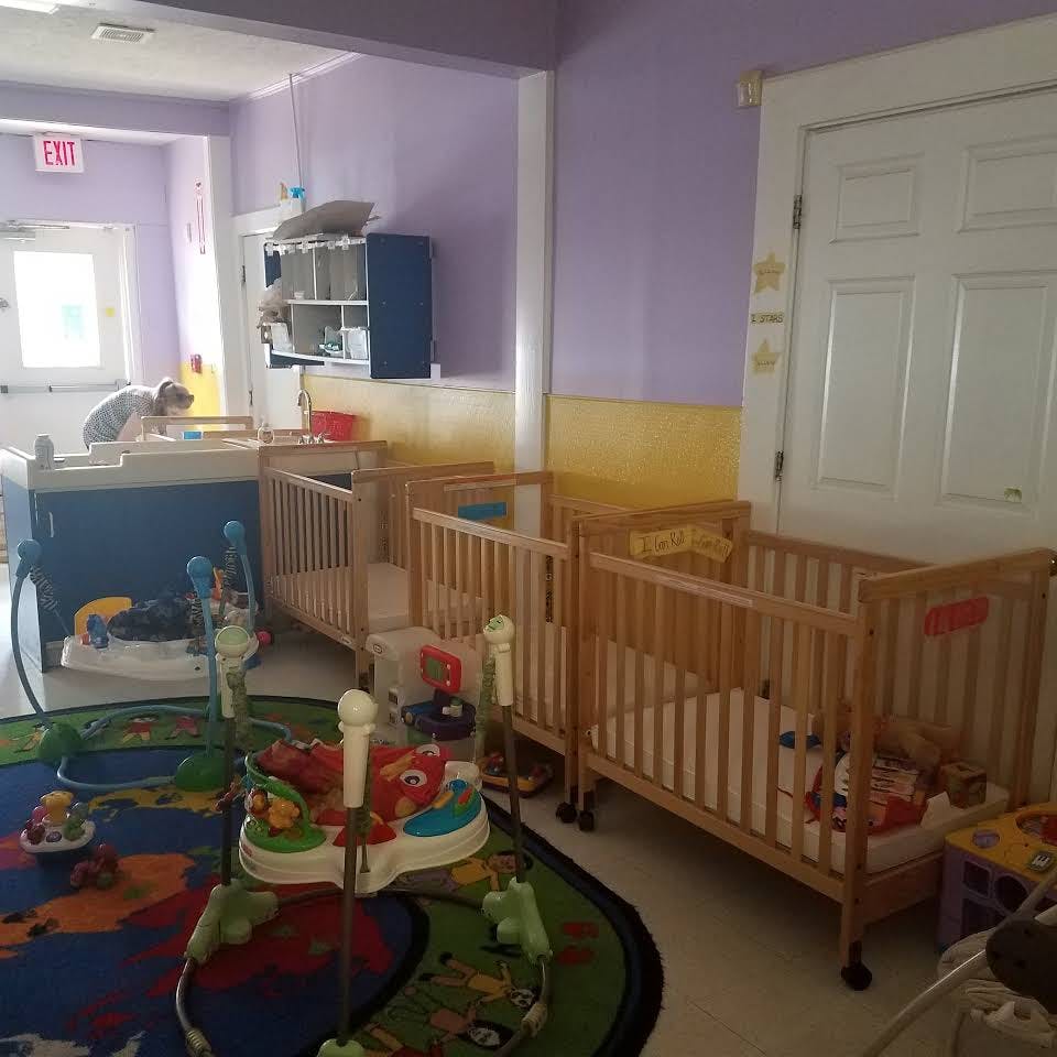 Cribs and play area in a room with a person in the background
