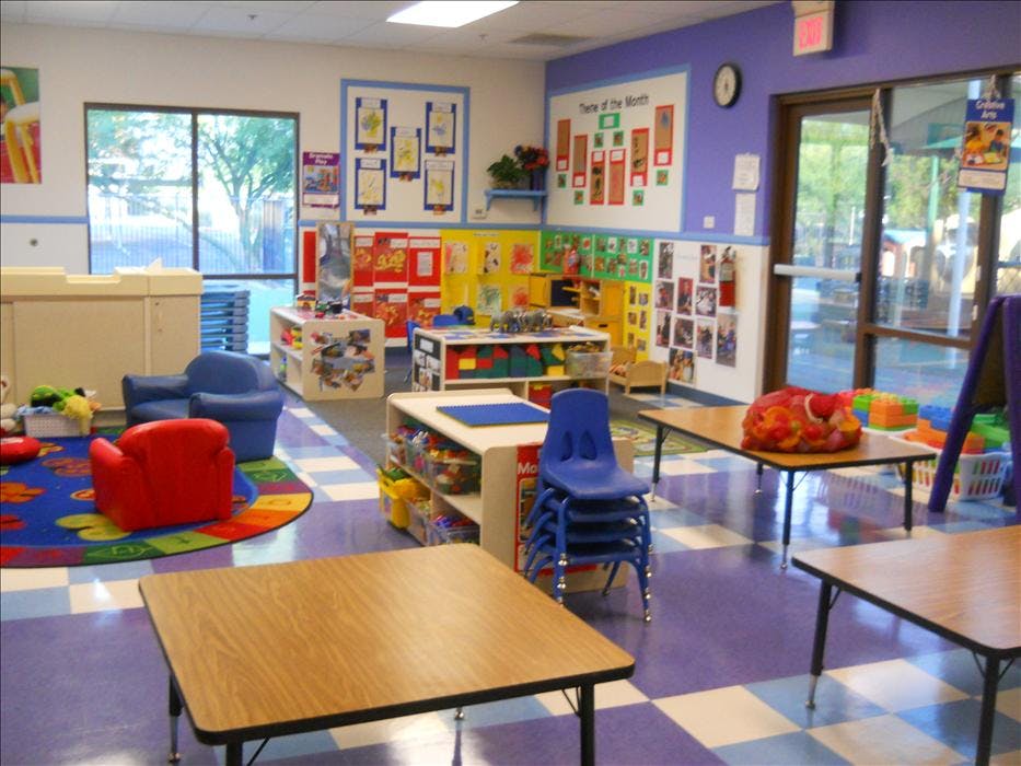 Colorful playroom with small tables, chairs, and learning stations