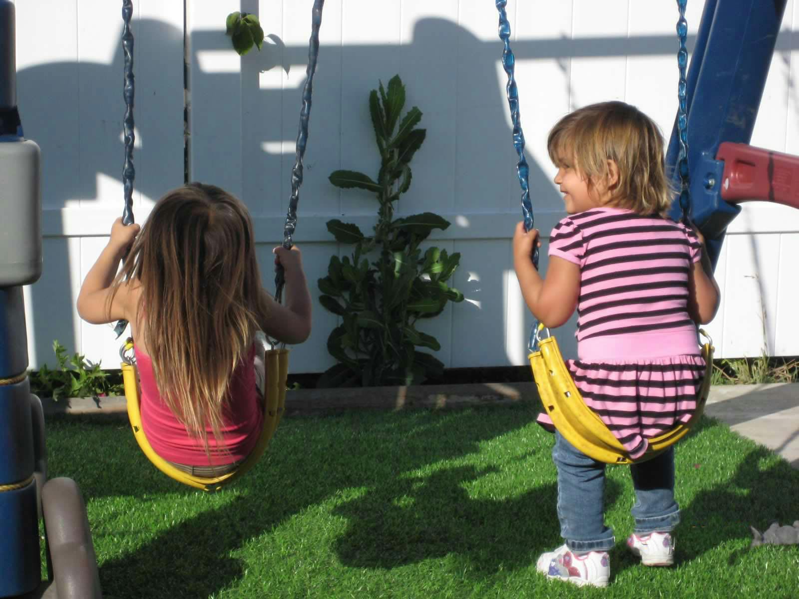 Two children on swings in a yard