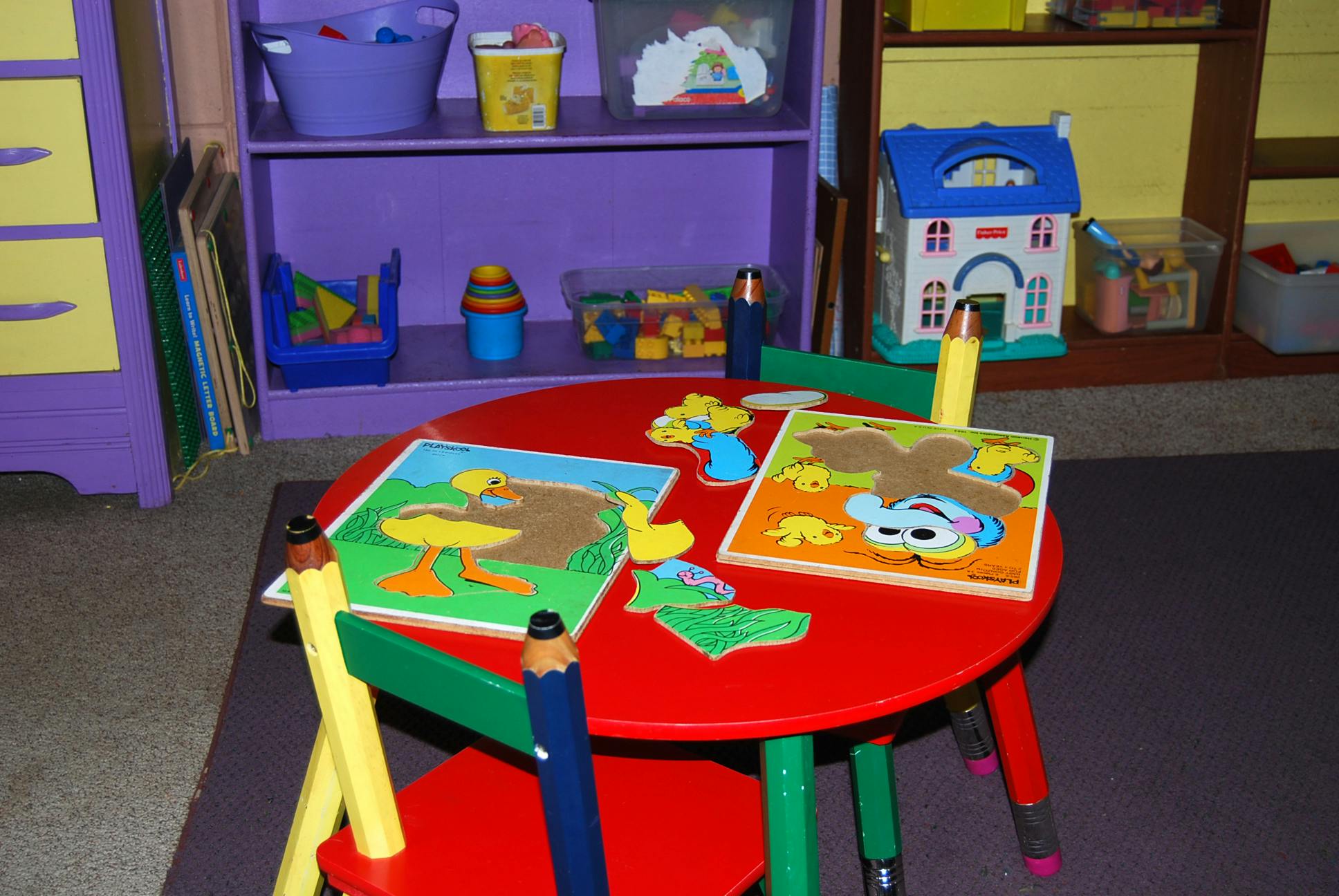 Puzzles and toys on a red table in a classroom