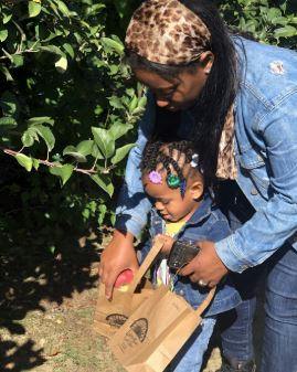 Person helping a child put apples into a paper bag