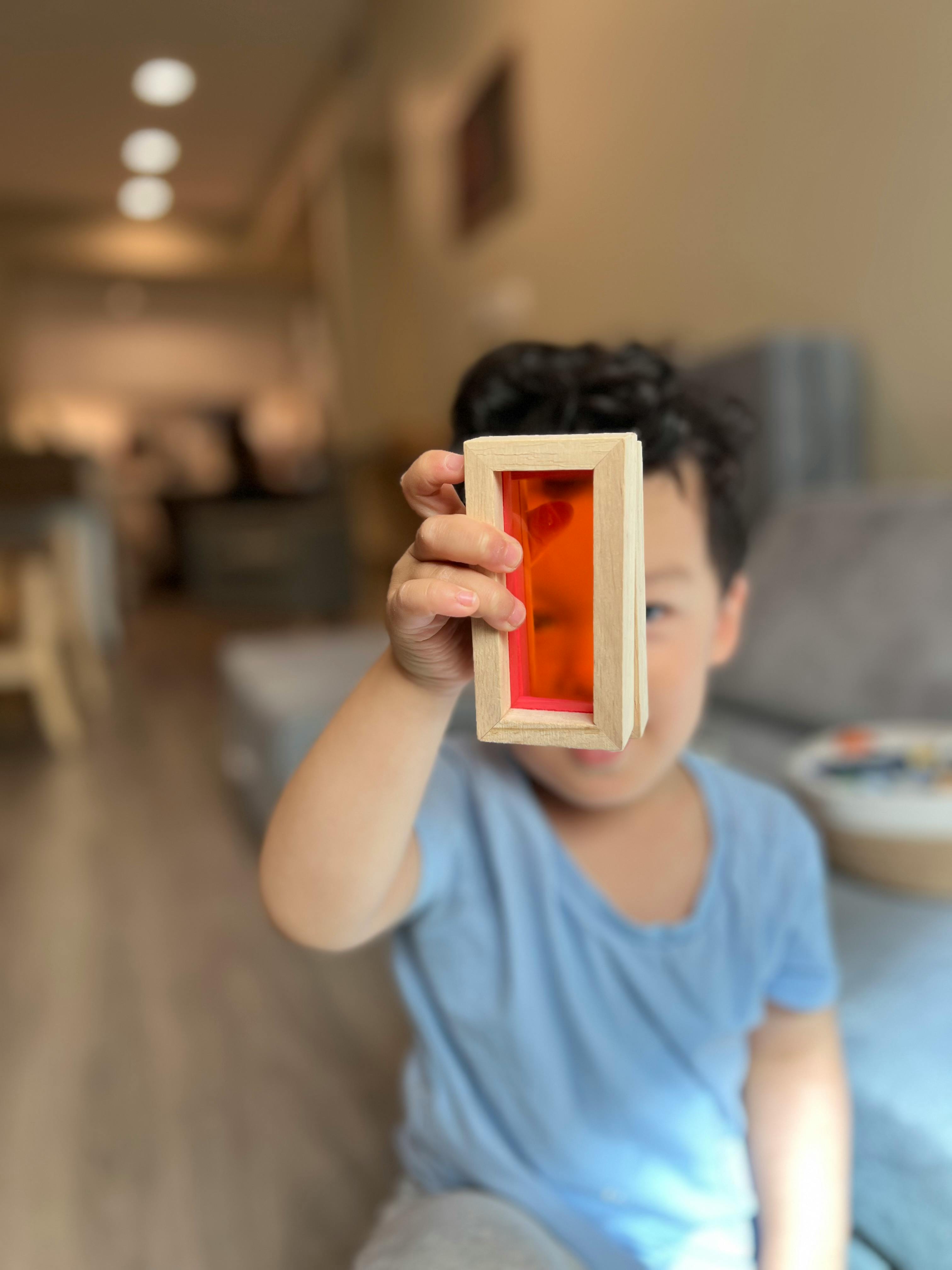 Child holding a wooden block with an orange transparent center