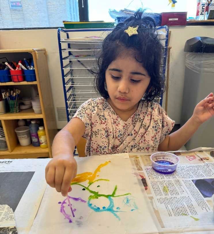 Child painting on paper with a cotton swab in a classroom