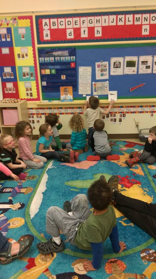 Children sitting on a rug in a classroom