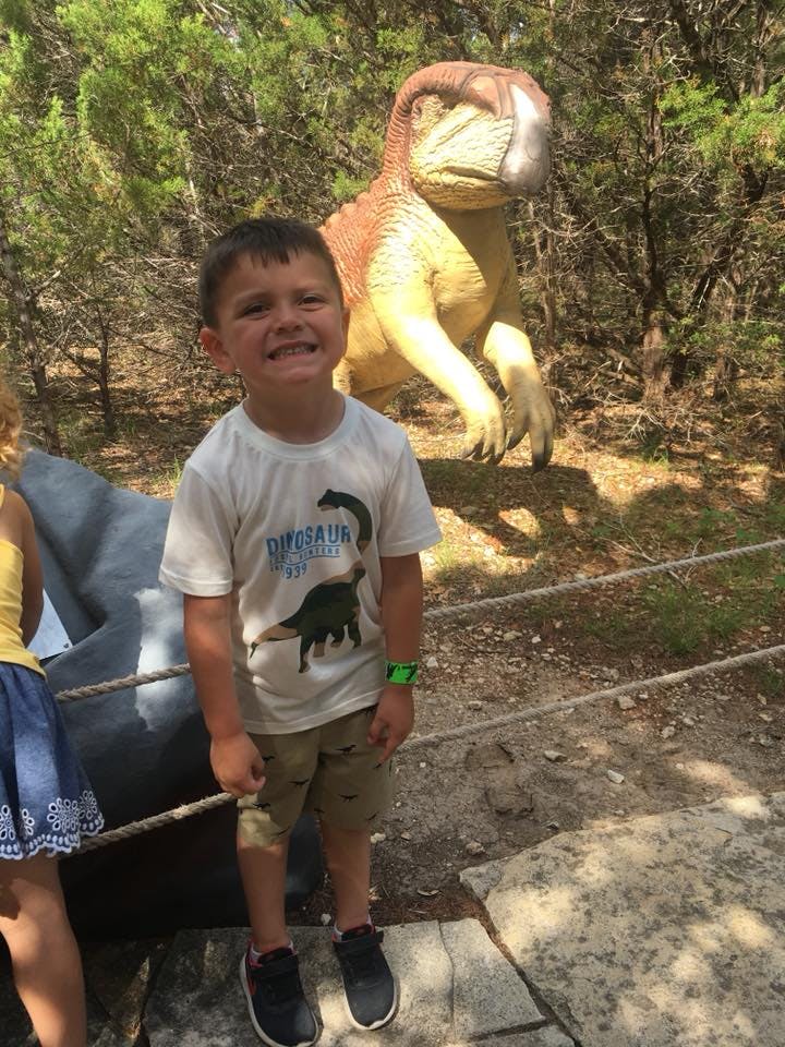 Child standing in front of a dinosaur statue