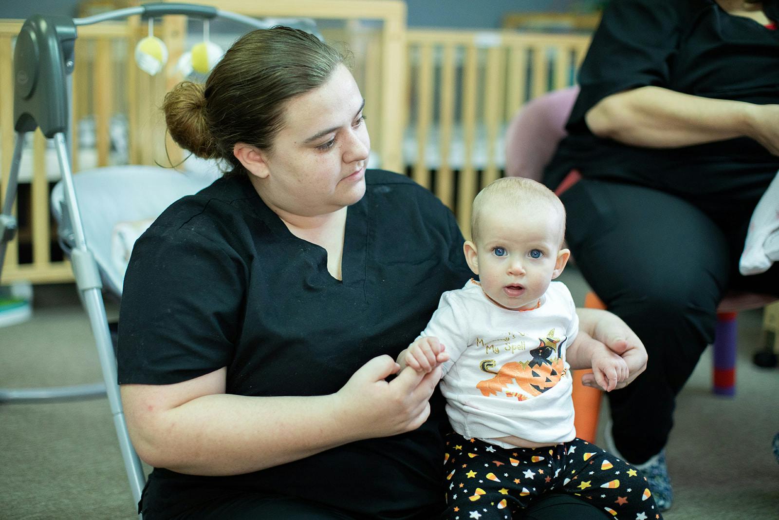 Person holding a child in a child in a room with cribs