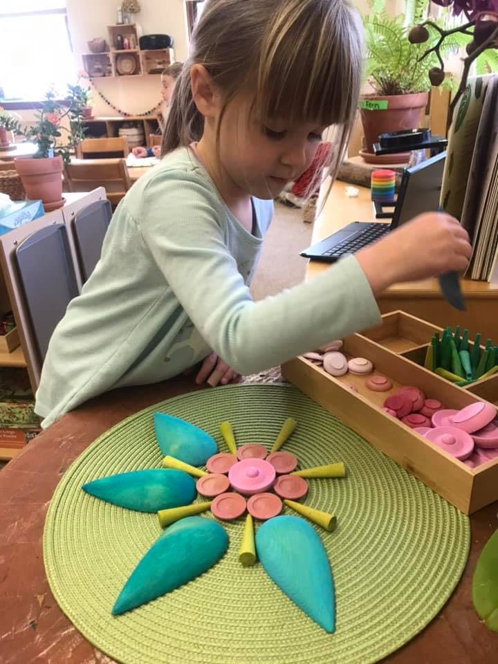 Child playing with colorful wooden pieces on a green mat