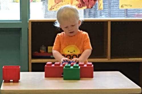 Child playing with large building blocks on a table