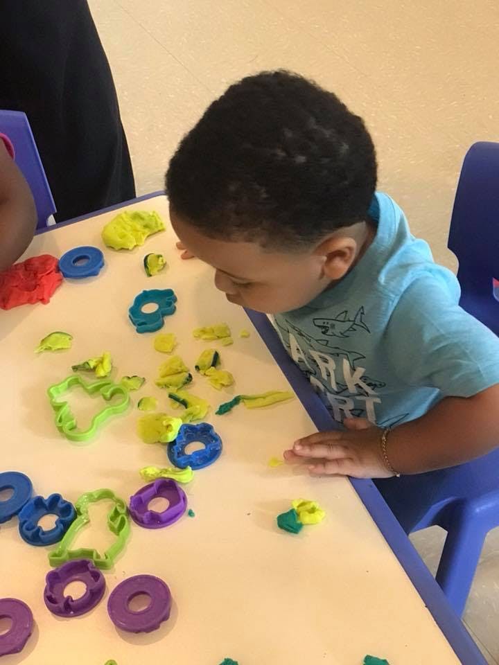 Child looking at playdough and cookie cutters on a table