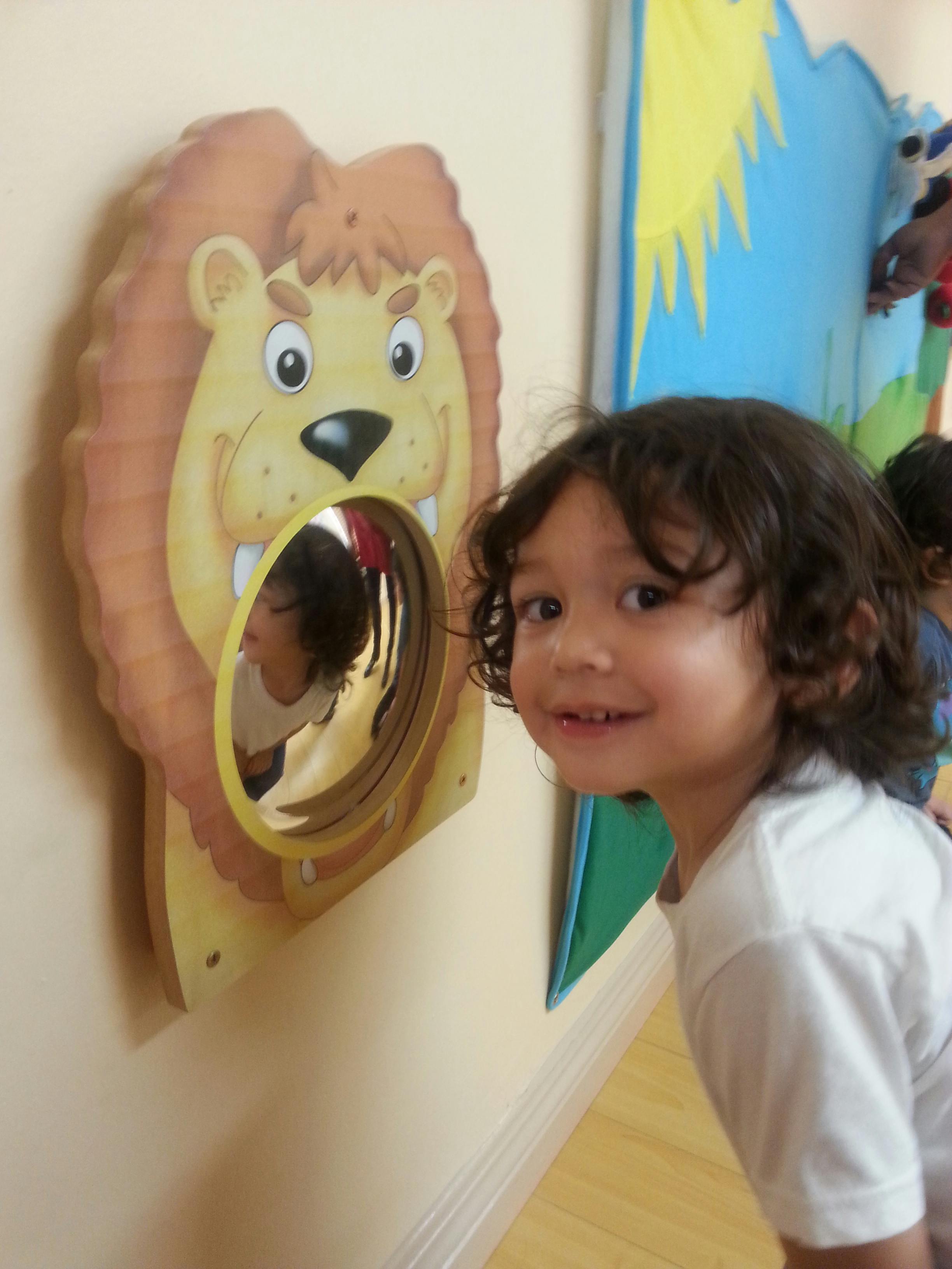 Child smiling next to a lion-shaped mirror toy