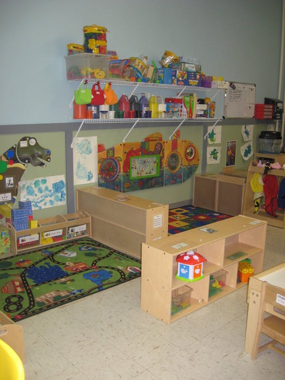 Classroom with shelves of supplies, play mats, and wooden furniture