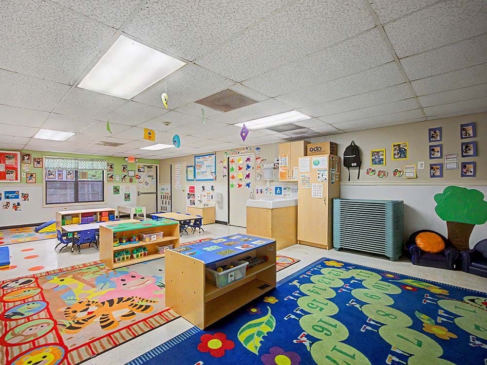 Children's classroom with colorful rugs, small tables, and learning materials