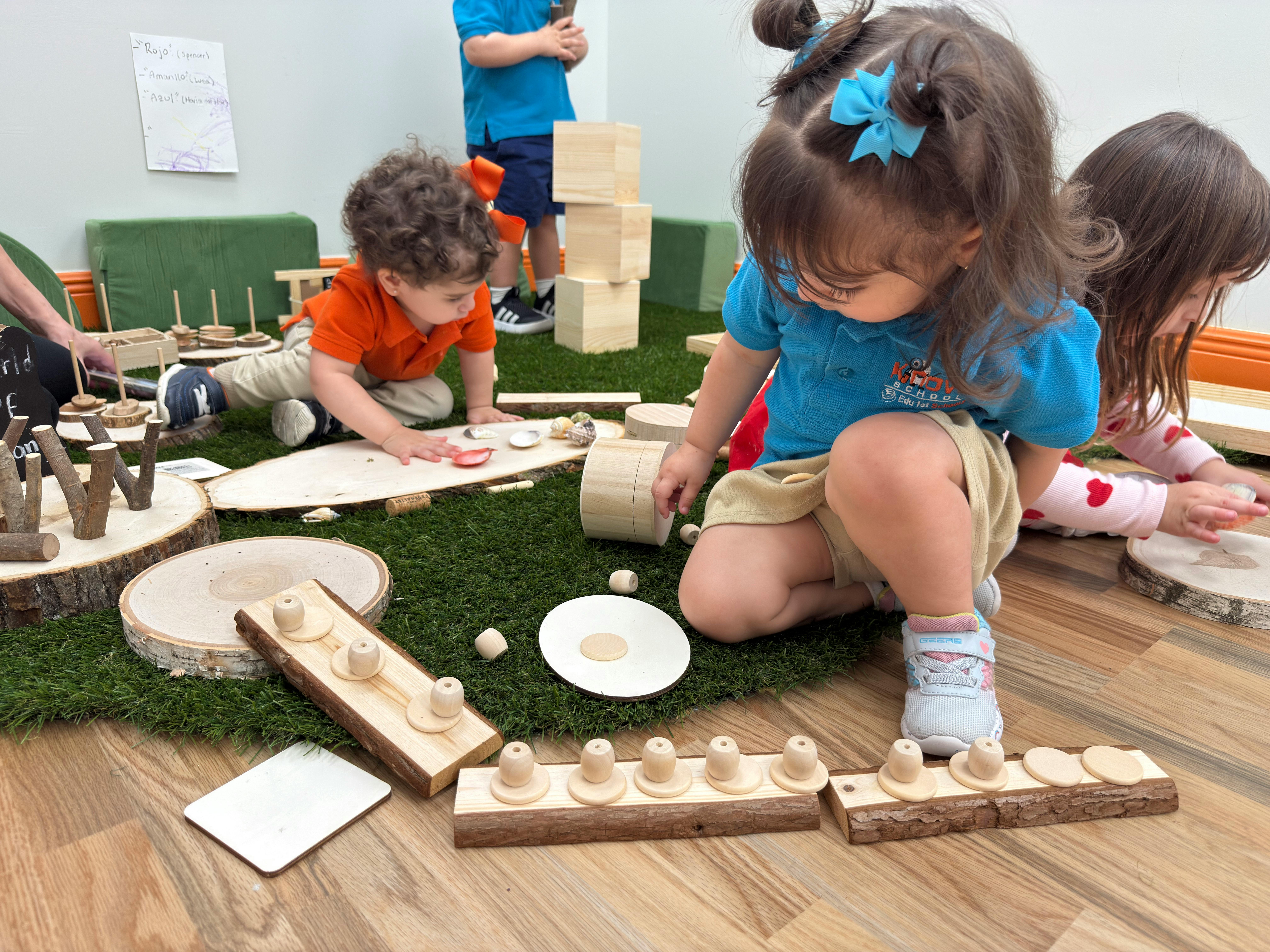 Children playing with wooden blocks and toys on a green mat