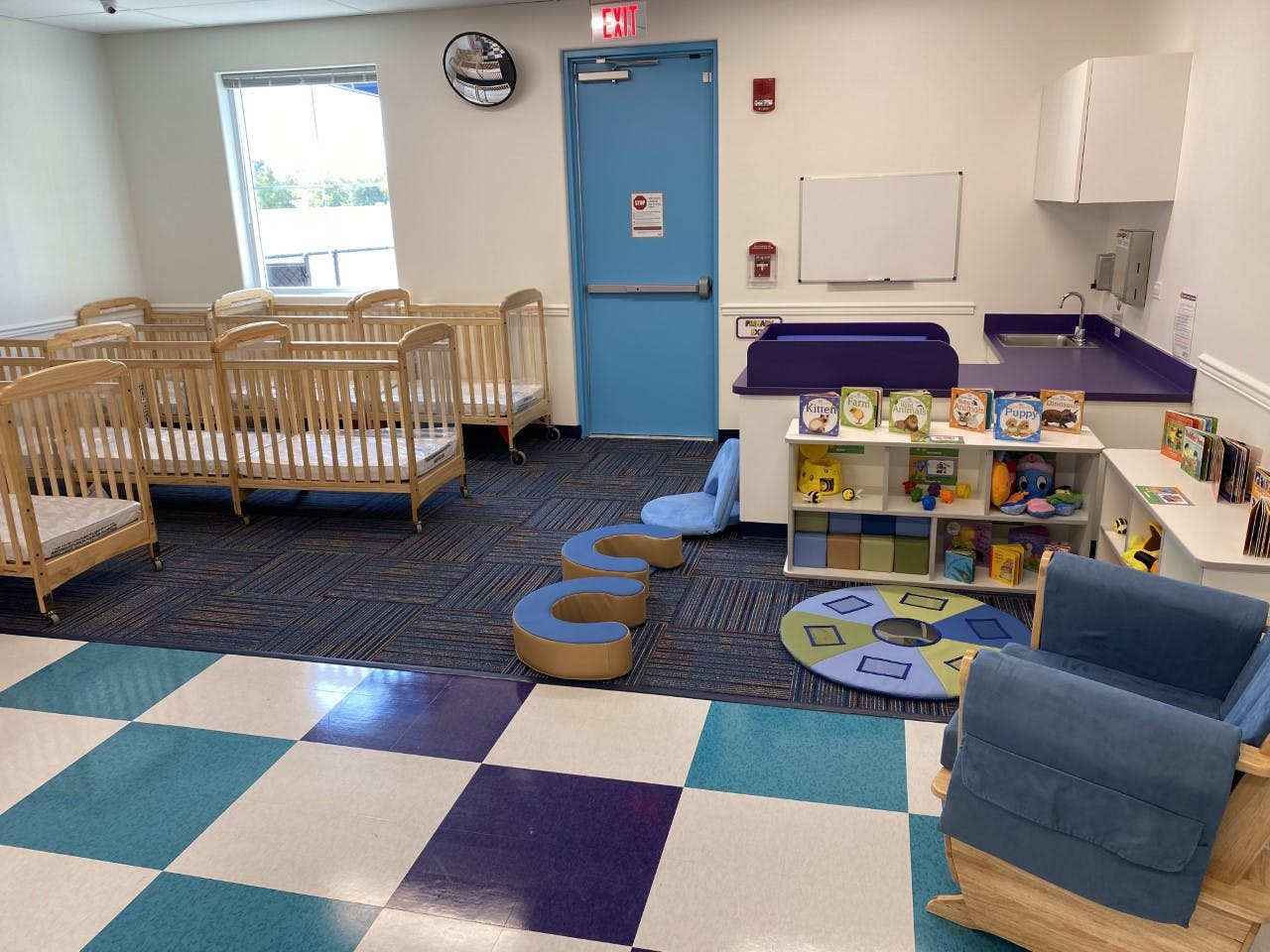 Nursery room with multiple cribs, changing station, and play area