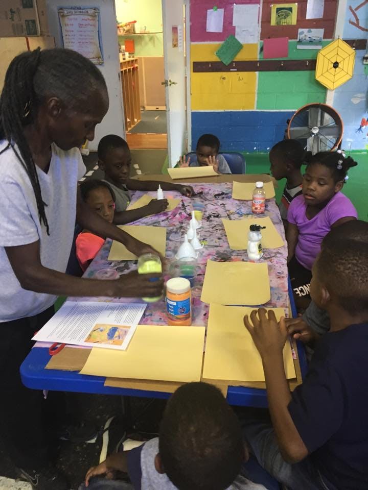 Person and children at a table doing an art activity