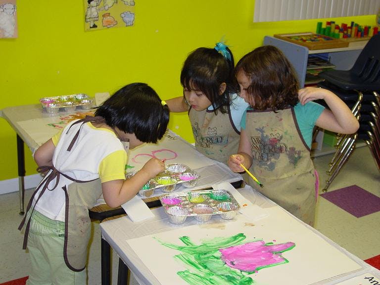 Three children painting at a table
