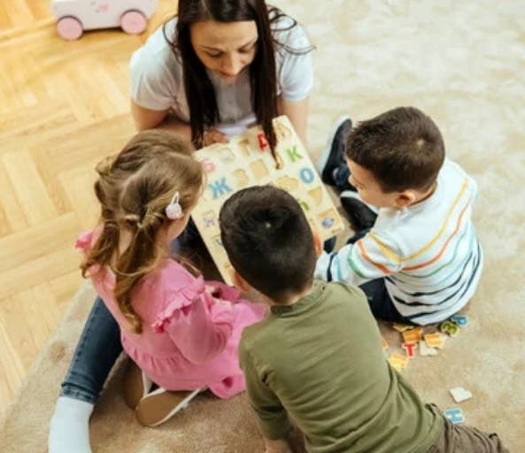Person and three children looking at a puzzle with letters
