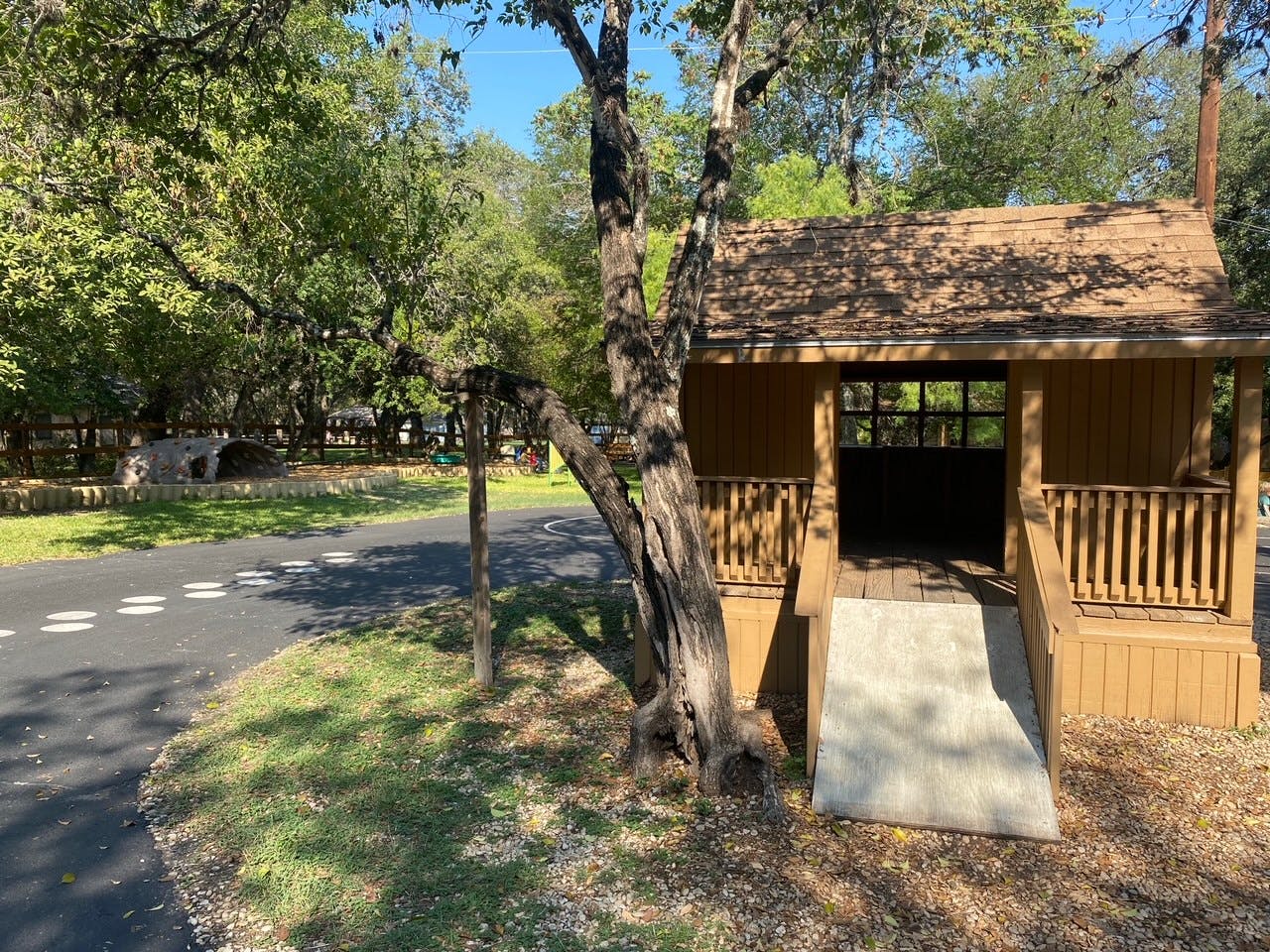 Small wooden building with a ramp and porch next to a paved road