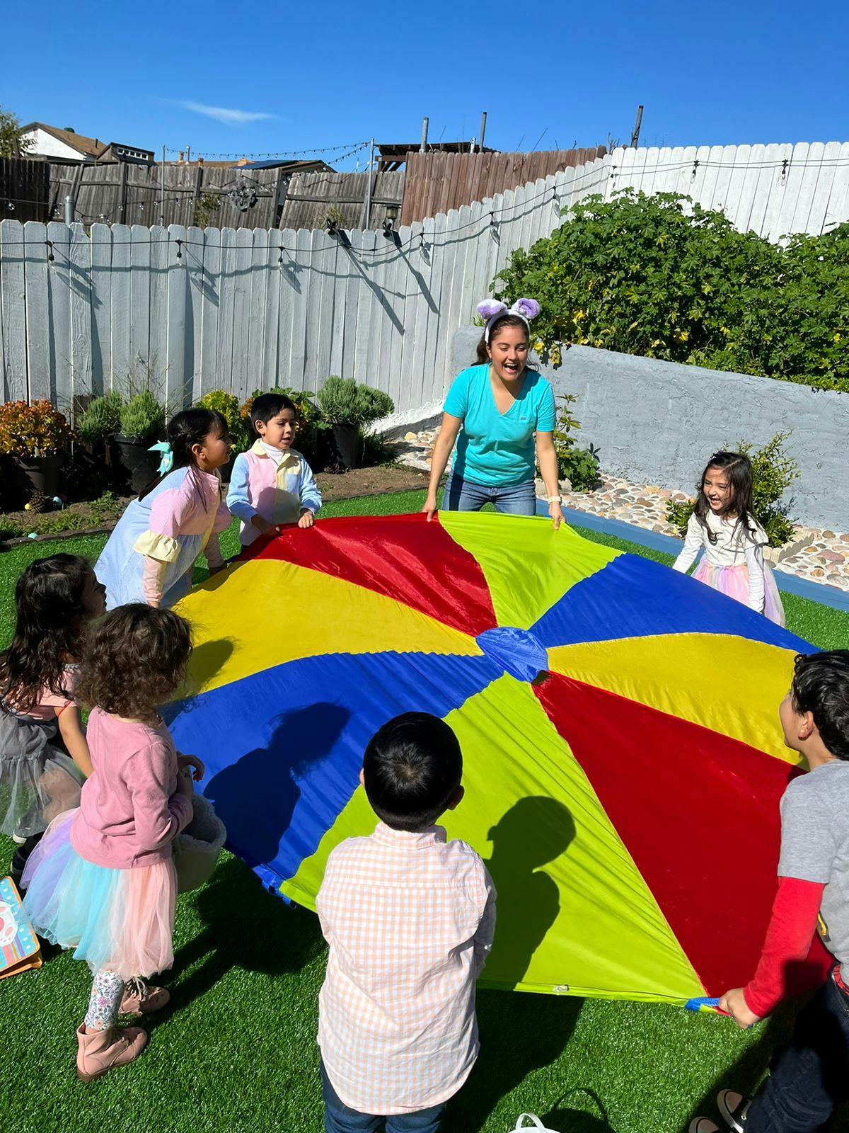 Adult and children playing with a colorful parachute outdoors