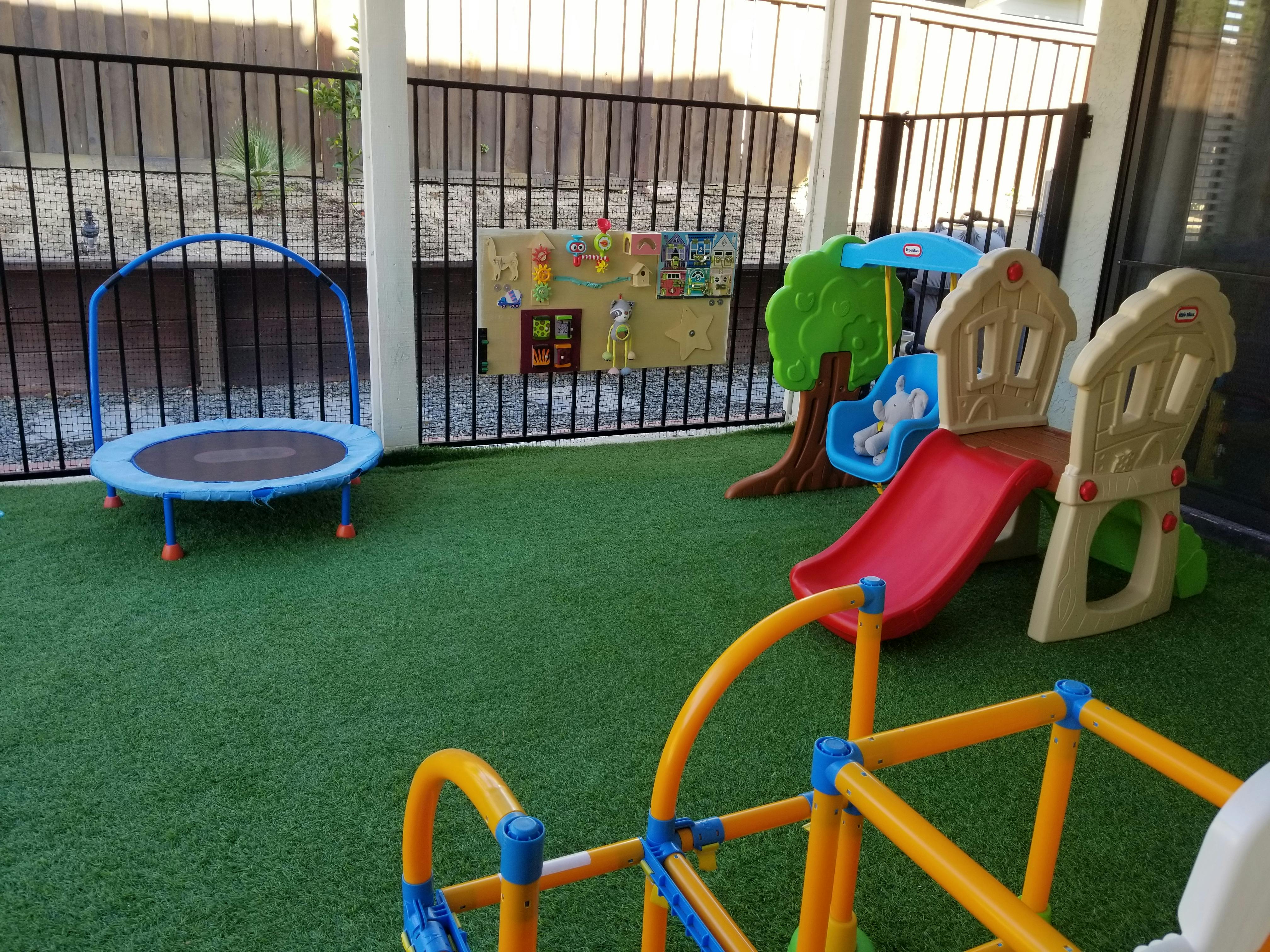 Outdoor play area with a small trampoline, slide, and climbing structure