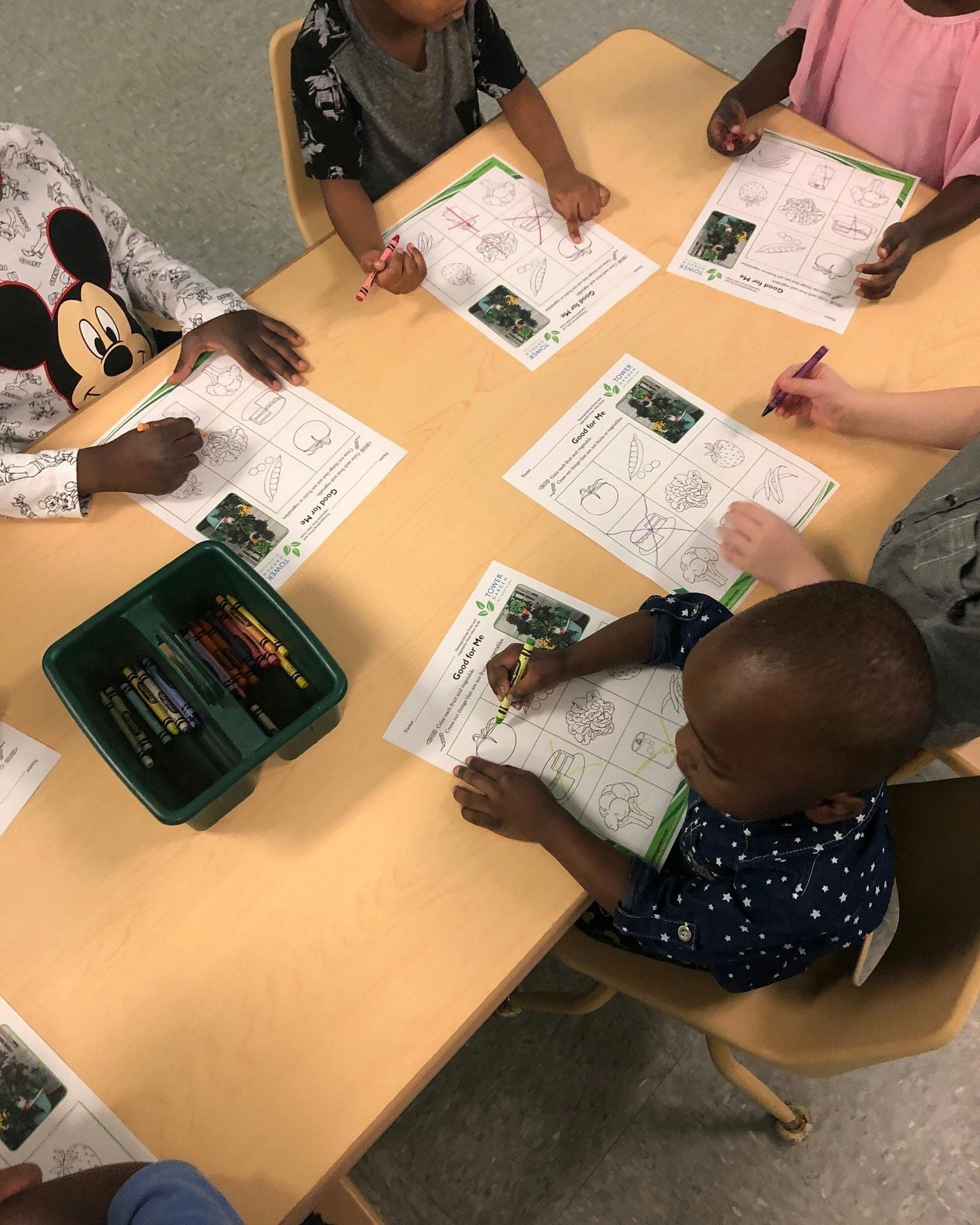 Children sitting at a table coloring worksheets