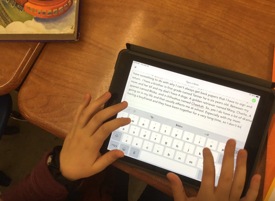 Child typing on a tablet with both hands