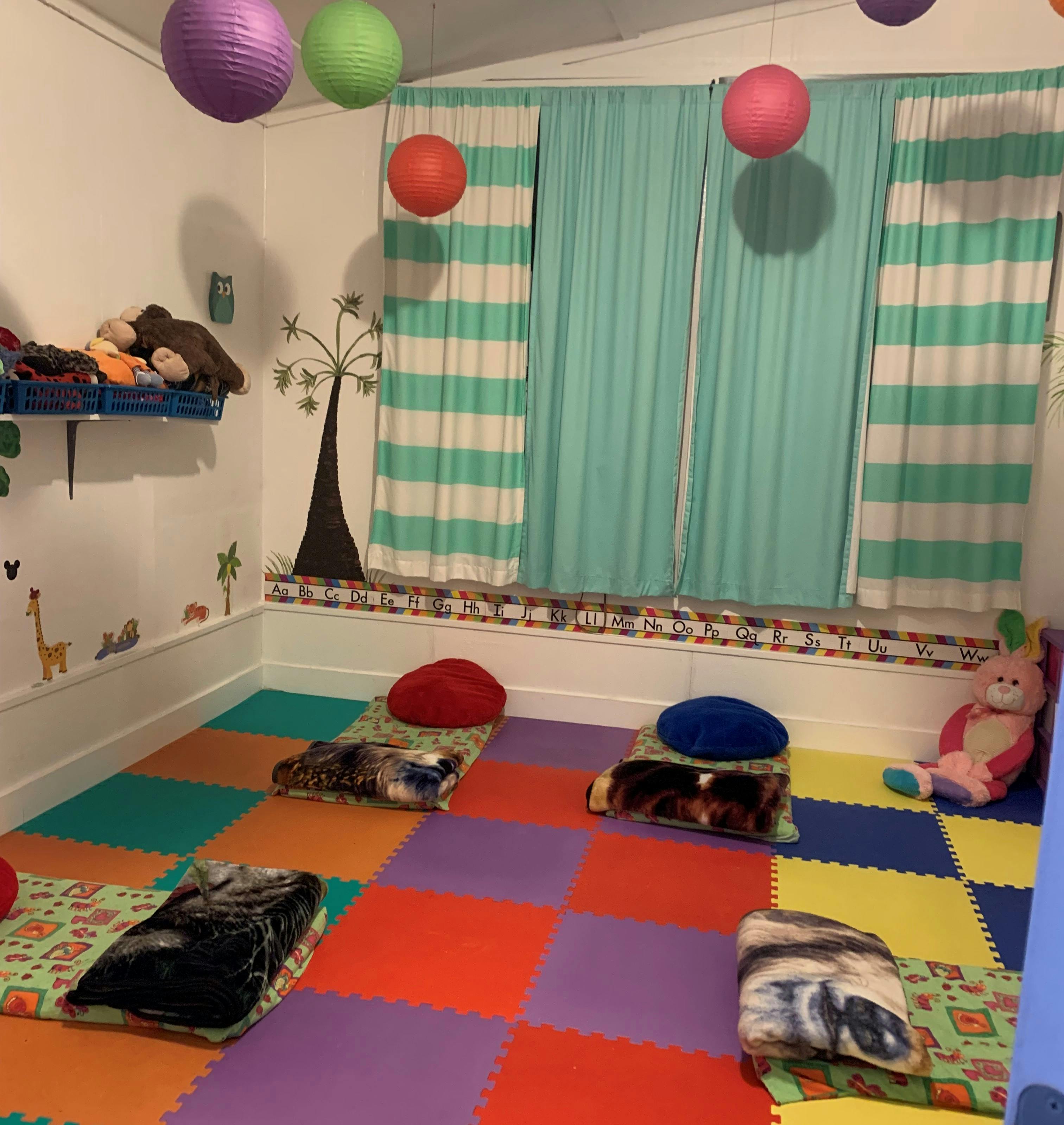 Room with colorful floor mats, pillows, and blankets on the floor