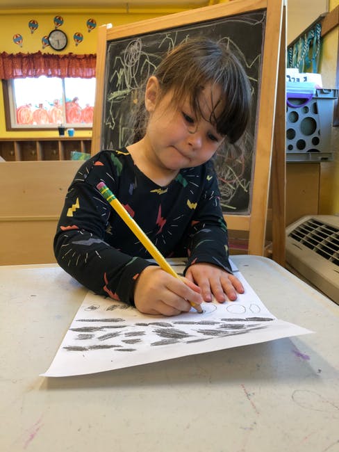 Child drawing on paper with a pencil