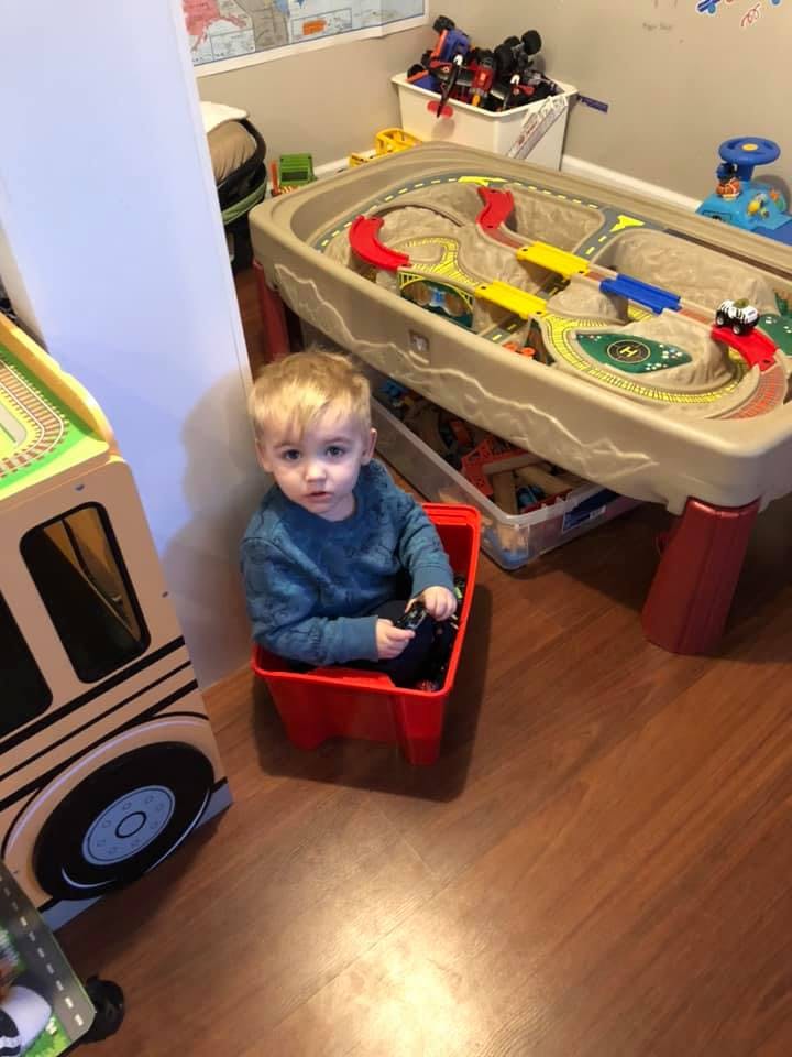 Child sitting in a red bin in a playroom