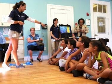Adult speaking to children and adults in a room
