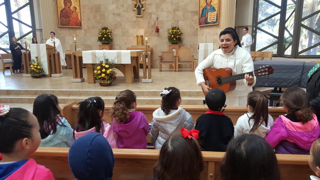Person playing guitar for children in a church
