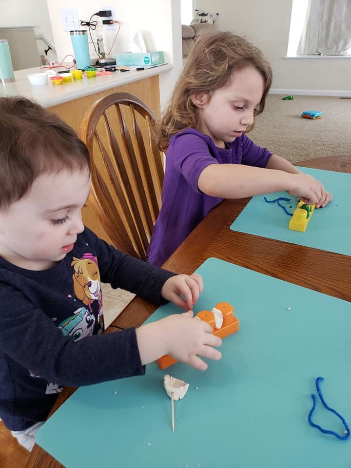 Two children playing with craft materials at a table
